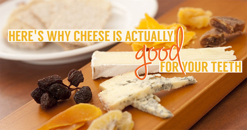 Assorted cheeses on a board with raisins and crackers, with text stating 'Here's why cheese is actually good for your teeth', emphasizing dental health benefits